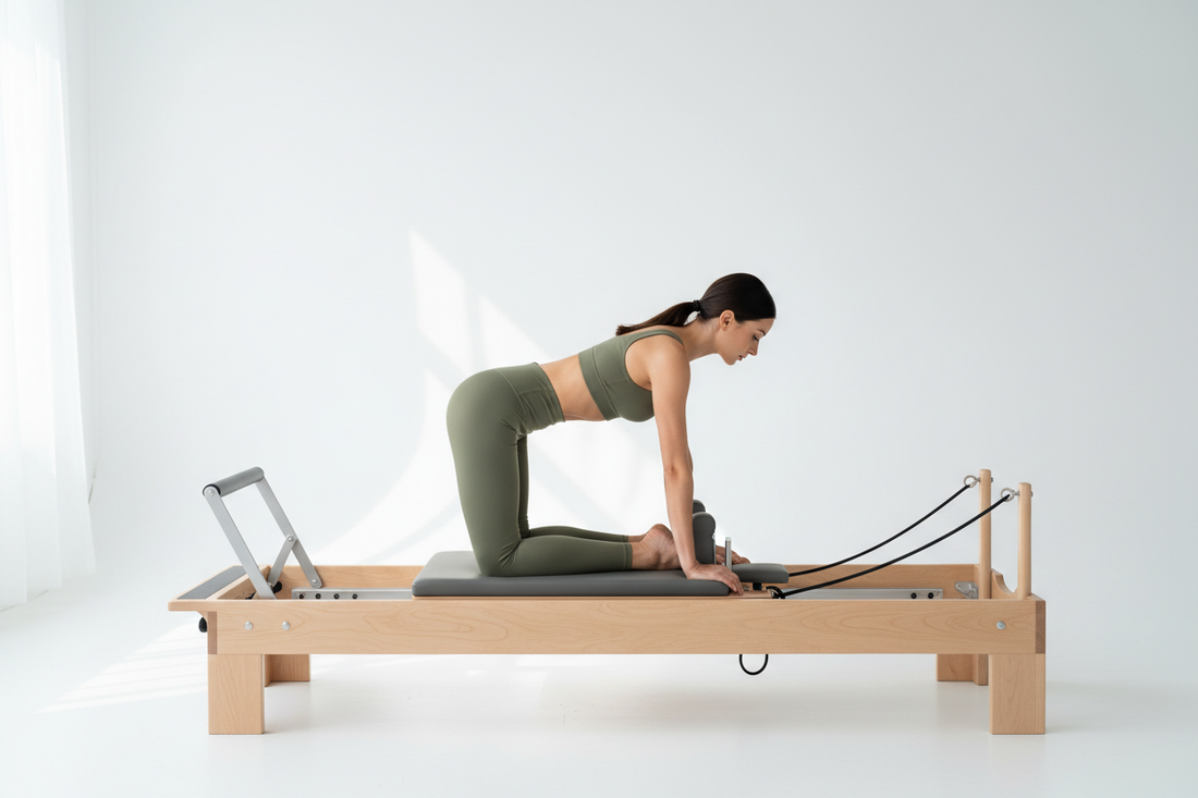 Woman in olive green high-waisted sculpting leggings and sports bra kneeling on a Pilates reformer carriage in a bright clean studio performing a core stabilization movement
