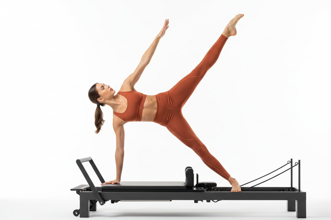 Athletic woman in terracotta orange compression leggings and sports bra executing an advanced side plank leg lift on a Pilates reformer under crisp studio lights